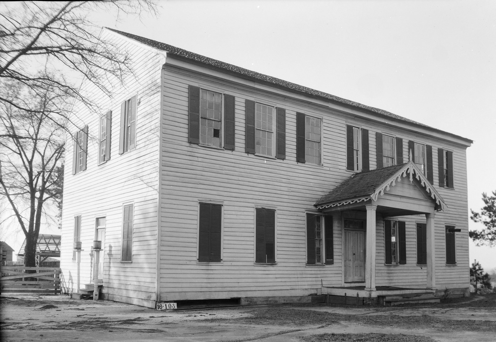 A two-story white clapboard hall with shuttered windows and a small gabled porch with ornamental woodwork, photographed in black and white in 1934.
